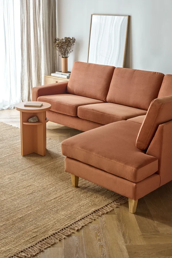sofa z ceglastą tapicerką w jasnym salonie